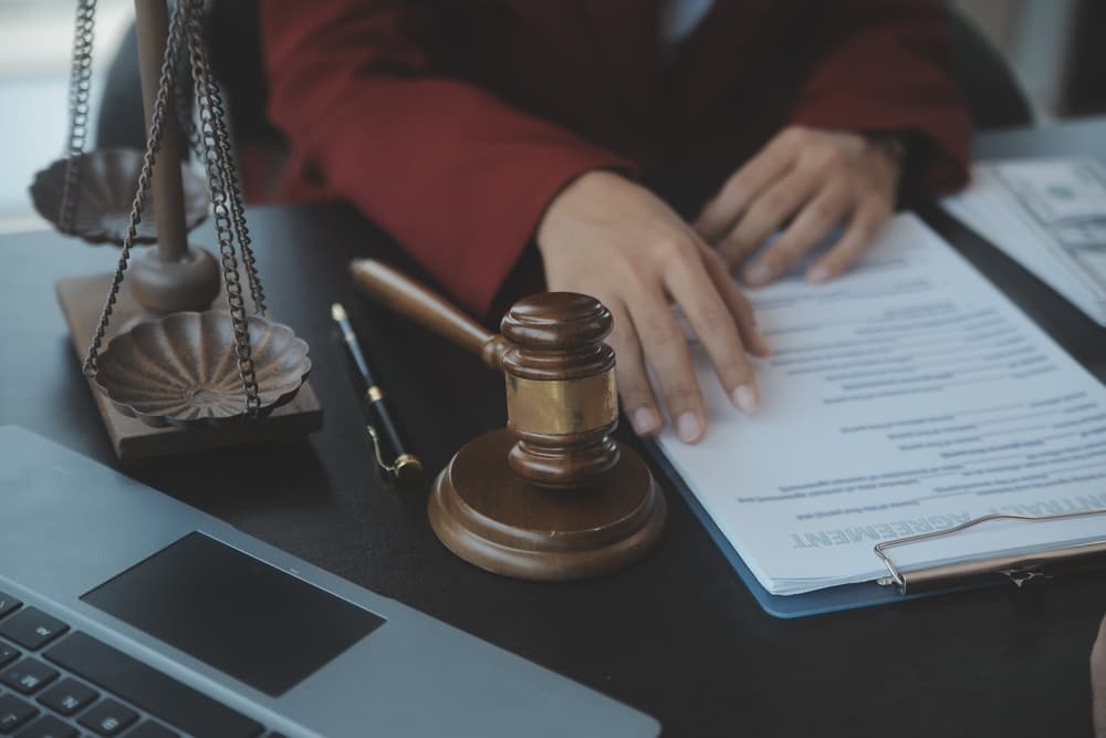 In the courtroom, a judge sits with a gavel, computer, and keyboard, symbolizing legal proceedings.