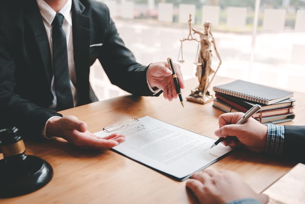 A lawyer signing documents in a courtroom.