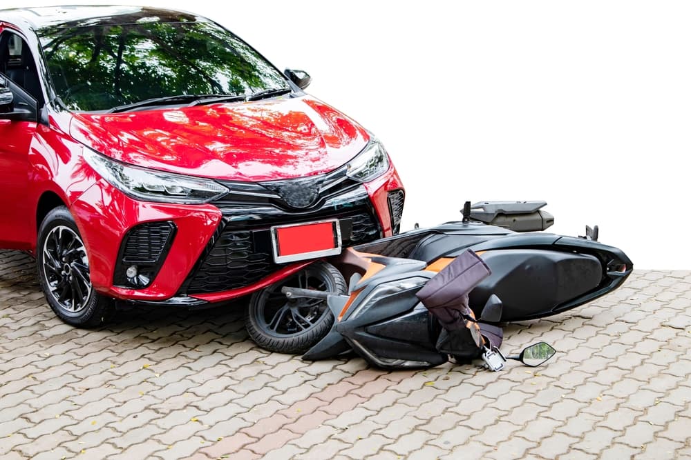 Car crash on road involving automatic transmission car and motorbike. Front bumper damaged.
