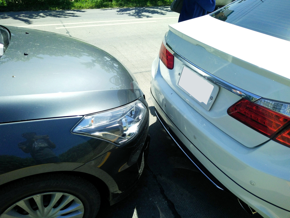 Two vehicles involved in a sideswipe collision while driving side by side on a multi-lane road or highway.